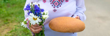 Grandmother with Ukrainian bread in her hands. Selective focus.