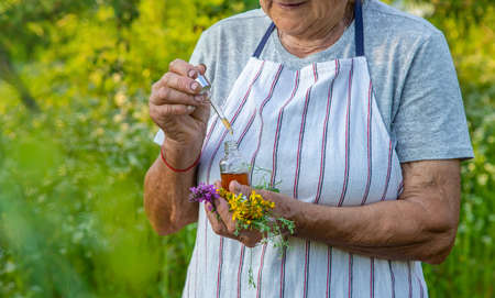 Old woman makes herbal tincture. Selective focus.の写真素材