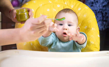 Little baby is eating broccoli vegetable puree. Selective focus.の写真素材