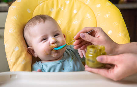 Little baby is eating broccoli vegetable puree. Selective focus.の写真素材