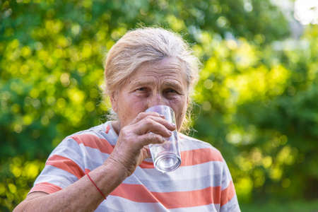 Grandmother drinks water from a glass. selective focus. drink.の写真素材