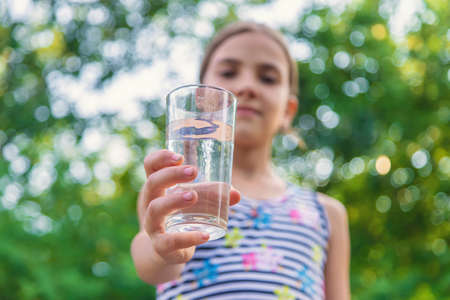 The child drinks water from a glass. Selective focus. Kid.の写真素材