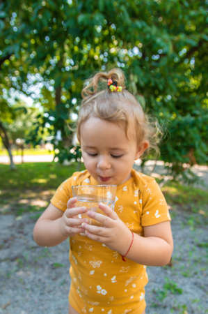 The child drinks water from a glass. Selective focus. Kid.