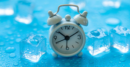 Clock and ice cubes. Vacation and daylight saving time concept. selective focus. blue,の写真素材