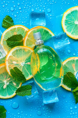 Perfume on a blue background with ice cubes and mint lemon. selective focus. Spa.の写真素材