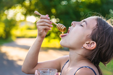A child eats honey in the park. selective focus. kid.の写真素材