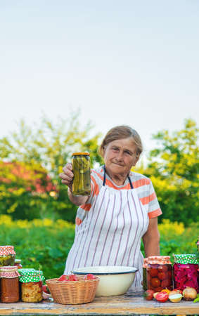 Senior woman preserving vegetables in jars. Selective focus.の写真素材