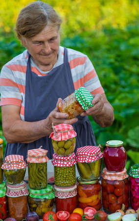 Senior woman preserve vegetables in jars. selective focus. food.の写真素材