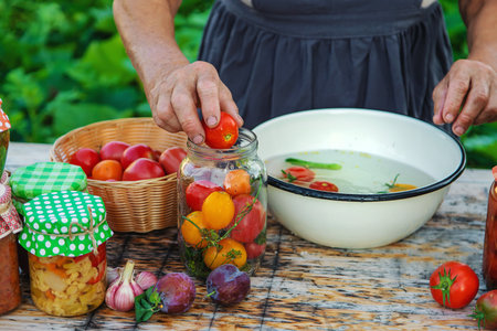 Senior woman preserve vegetables in jars. selective focus. food.の写真素材