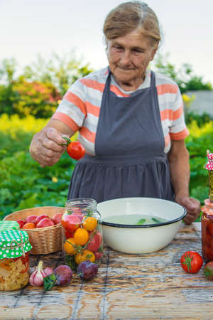 Senior woman preserve vegetables in jars. selective focus. food.の写真素材