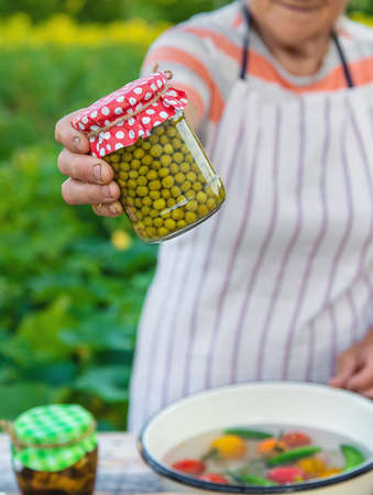 Senior woman preserve vegetables in jars. selective focus. food.の写真素材