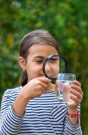 The child examines the water with a magnifying glass. selective focus. kid.の写真素材