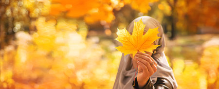 Muslim girl with autumn leaves. Selective focus.の写真素材