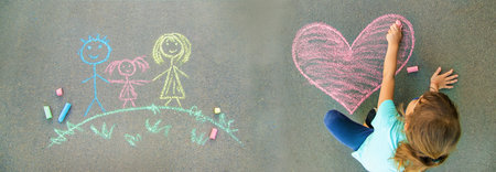the child paints chalk on the asphalt heart. Selective focus.の写真素材