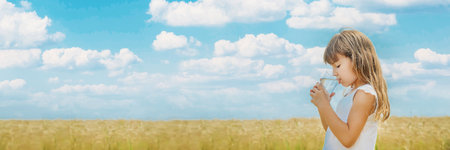 A child drinks water on the background of the field. Selective focus.の写真素材