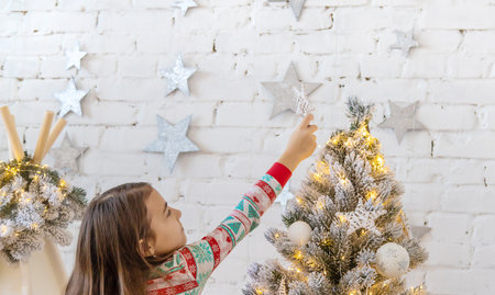 A child hangs a star on a Christmas tree. selective focus. kid.の写真素材