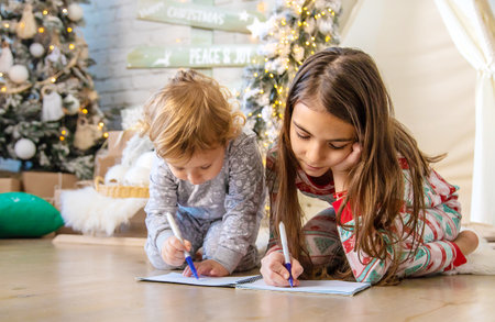 Children write a letter to Santa under the tree. selective focus. kid.の写真素材