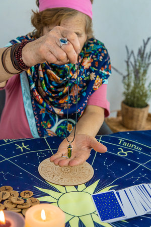 Woman fortune teller fortune telling pendulum. Selective focus.の写真素材
