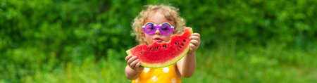 A child eats watermelon in the park. selective focus. kid.の写真素材