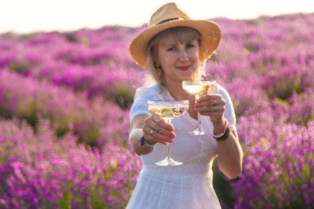 A woman drinks wine in a lavender field. Selective focus. Nature.の写真素材