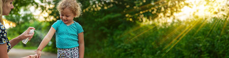 Mom sprays her child with mosquito repellent. Selective focus. Nature.の写真素材