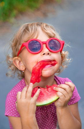 Child girl in the park eats watermelon. Selective focus. Food.の写真素材