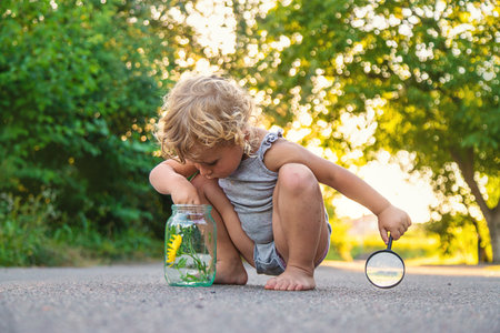 A child looks into a jar with a magnifying glass. Selective focus. Kid.の写真素材