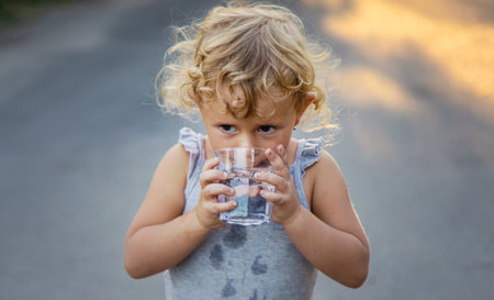 A child drinks water from a glass. Selective focus. Kid.の写真素材