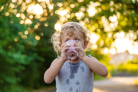 A child drinks water from a glass. Selective focus. Kid.の写真素材