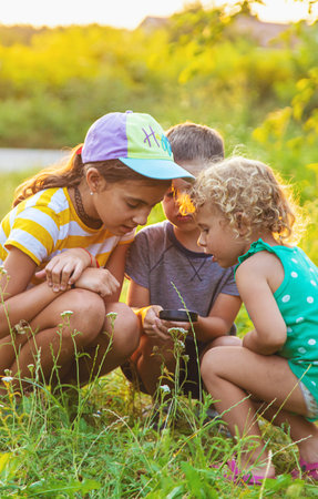 Children look through a magnifying glass together at the plants in the garden. Selective focus. Kid.の写真素材