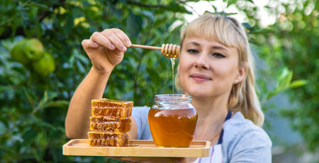 A woman holds honey in the garden. Selective focus. Nature.の写真素材