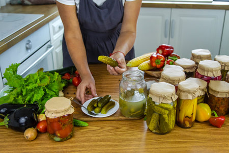 Woman canning vegetables in jars in the kitchen. Selective focus. Food.の写真素材