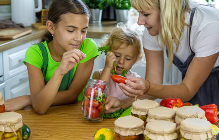 Family canning vegetables in jars in the kitchen. Selective focus. Food.の写真素材