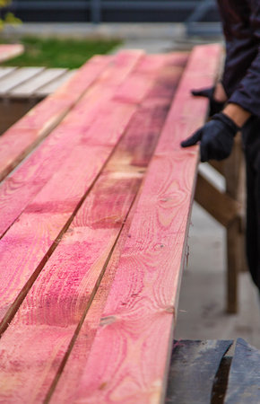 A man treats a board with a red antiseptic. selective focus. Nature.の写真素材