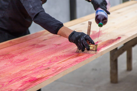A man treats a board with a red antiseptic. selective focus. Nature.