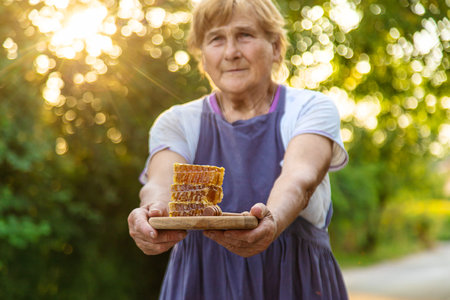 An elderly woman holds honey in her hands, selective focus. People.の写真素材