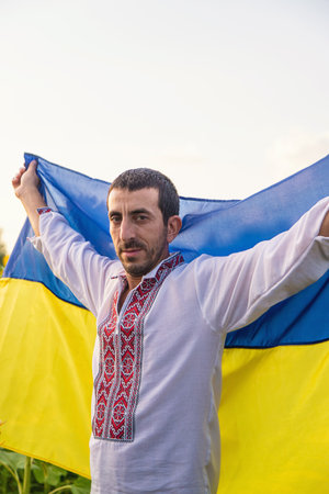 Man in a sunflower field wearing an embroidered shirt. Selective focus.の写真素材