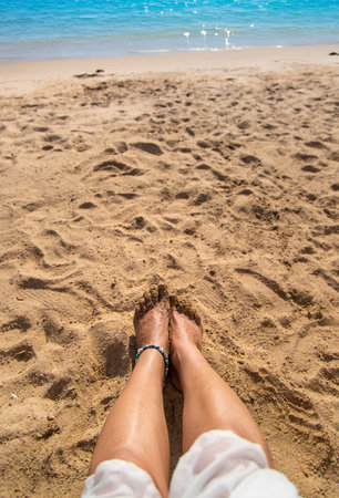 A person's feet on the beach.