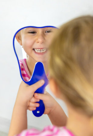 A child examining his teeth in a mirror. Selective focus.