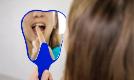 A child at the dentists office examining his teeth in a mirror. Selective focus.の写真素材