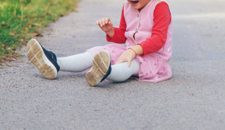The child fell on the road and hit her leg. Selective focus.の写真素材