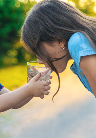 The child drinks water from a glass. Selective focus.の写真素材