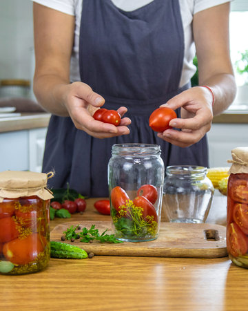 Woman canning vegetables in jars in the kitchen. Selective focus.の写真素材
