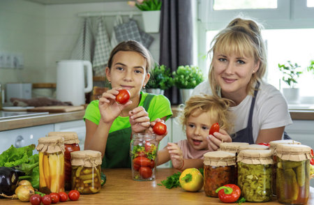 Family canning vegetables in jars in the kitchen. Selective focus.の写真素材