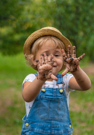 a child in the dirt in the garden holds the soil in his hands. Selective focus.