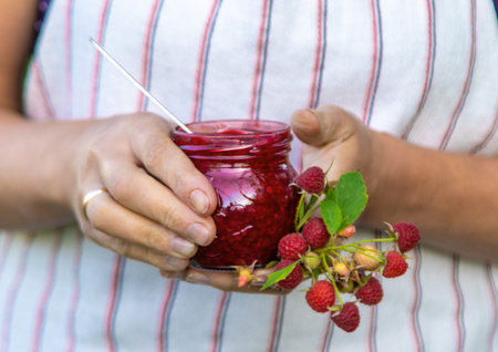 Raspberry jam in the hands of a woman. Selective focus.の写真素材
