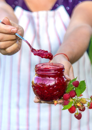 Raspberry jam in the hands of a woman. Selective focus.の写真素材