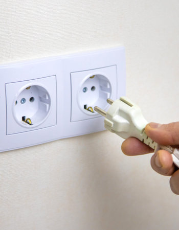 The man plugs in the cord. Selective focus.