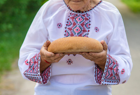 Grandmother with Ukrainian bread in her hands. Selective focus.