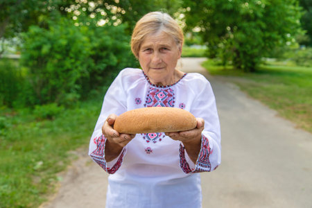 Grandmother with Ukrainian bread in her hands. Selective focus.